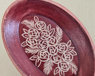 A small handmade oval-shaped dish decorated with a dozen little roses.