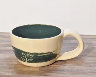 A lovely ceramic mug with little carved branches over brush strokes on the outside with a matching green on the inside.