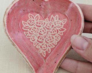 A small handmade heart-shaped dish decorated with a dozen little roses.