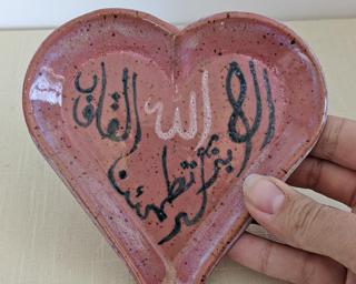 A pretty handmade heart-shaped dish decorated with Arabic calligraphy.