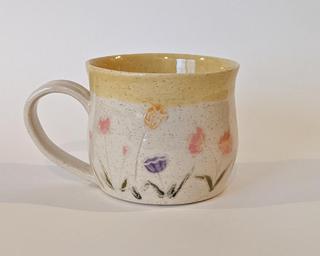 Mug with hand-painted flowers and a yellow glaze on the inside and around the rim.
