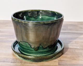 Adorn your home with this one of a kind ceramic planter, complete with a drain hole on the side and a small attached dish to catch any water overflow.