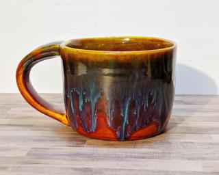 A hefty ceramic mug with a gorgeous  red and blue drip around the outside with a red and yellow on the inside.