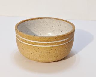 A small handle-less ceramic cup with a white glaze over a mid-fire speckled clay.