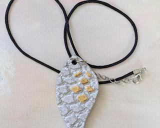 A lovely textured leaf pendant finished with a shiny gold lustre finish.