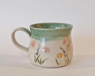 Mug with hand-painted flowers and a green glaze on the inside and around the rim.