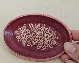 A small handmade oval-shaped dish decorated with a dozen little roses.