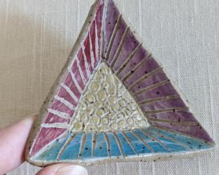 A small handmade oblong-shaped dish decorated with various colors and lines which has been carefully carved for added detail.
