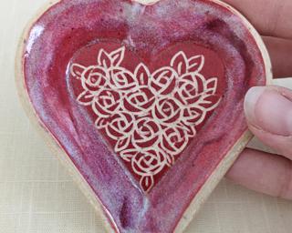 A small handmade heart-shaped dish decorated with a dozen little roses.